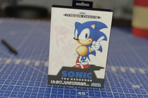 Caja de Sonic the Hedgehog para SEGA Mega Drive sobre una mesa azul con diseño cuadriculado.